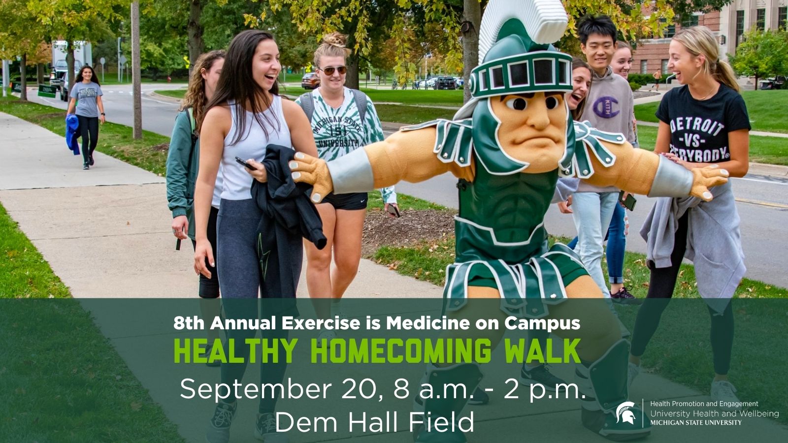 Sparty flexes his muscles in front of a sign advertising the Healthy Homecoming Walk. The event date and time appears to the right. 